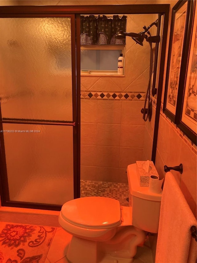 bathroom with tile patterned flooring, a shower with shower door, and tile walls