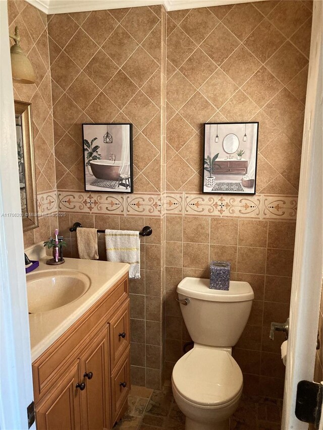 bathroom featuring crown molding, vanity, tile walls, and toilet