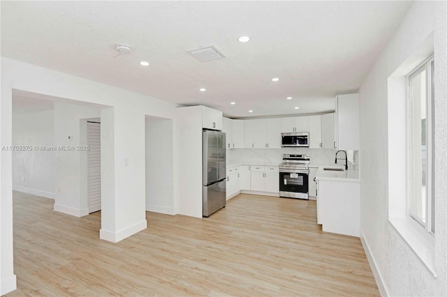 kitchen featuring sink, white cabinets, light wood-type flooring, and appliances with stainless steel finishes