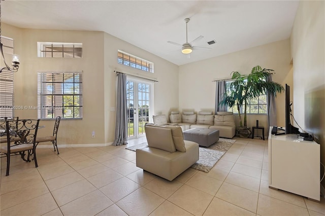 tiled living room featuring ceiling fan, a towering ceiling, and french doors