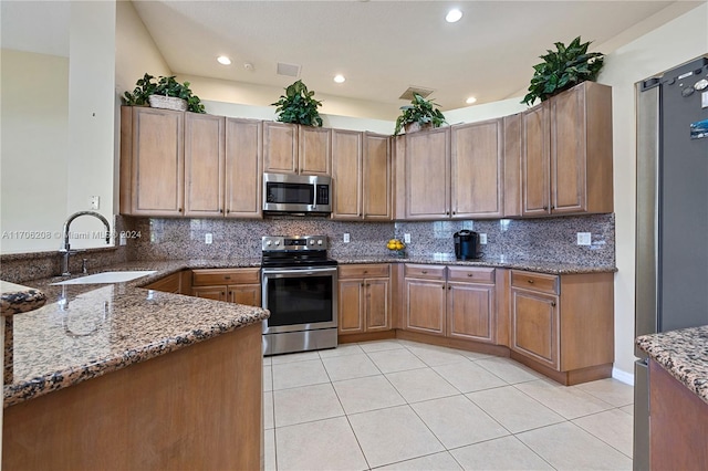 kitchen with decorative backsplash, appliances with stainless steel finishes, dark stone countertops, and sink