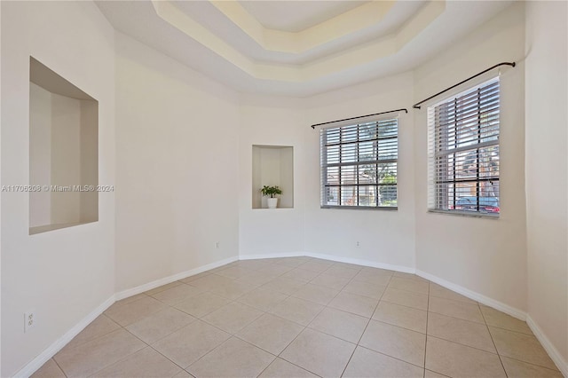 empty room featuring light tile patterned flooring and a tray ceiling