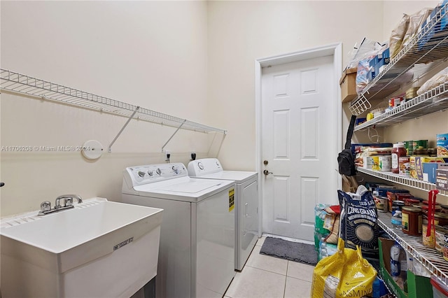 washroom featuring washing machine and dryer, light tile patterned floors, and sink