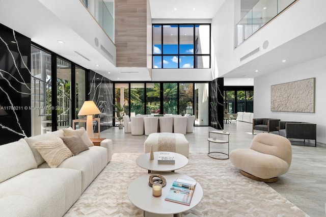 living room featuring expansive windows, a healthy amount of sunlight, and a towering ceiling