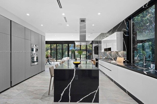 kitchen with a kitchen breakfast bar, tasteful backsplash, expansive windows, sink, and a large island