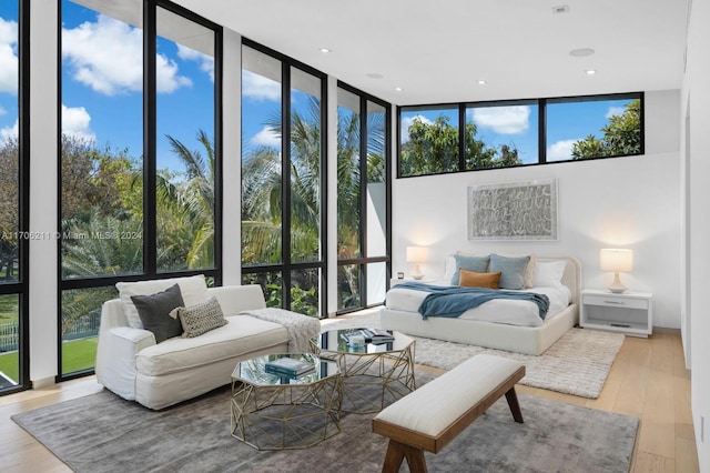 bedroom with floor to ceiling windows, light hardwood / wood-style floors, and multiple windows