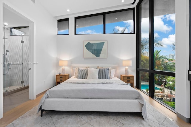 bedroom with hardwood / wood-style floors, expansive windows, and multiple windows