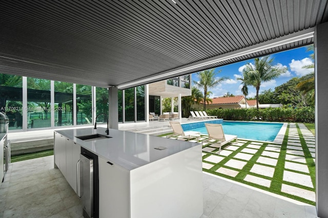 view of pool featuring a wet bar, a patio area, and exterior kitchen