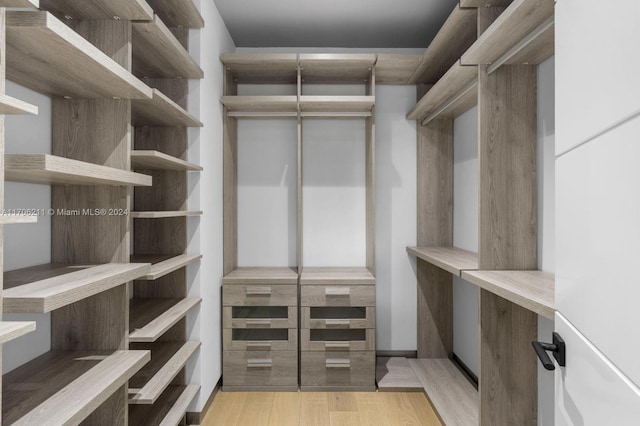 walk in closet with light hardwood / wood-style flooring