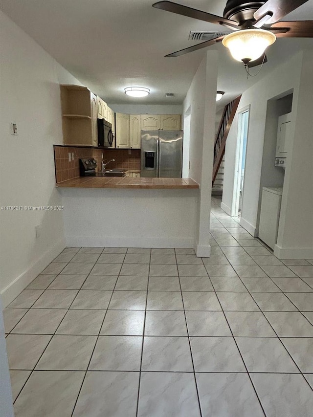 kitchen featuring stainless steel fridge, kitchen peninsula, decorative backsplash, and light tile patterned floors