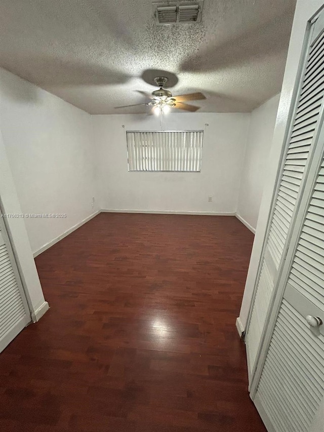 spare room with dark hardwood / wood-style flooring, a textured ceiling, and ceiling fan