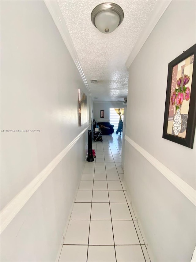 hall with light tile patterned floors, a textured ceiling, and ornamental molding