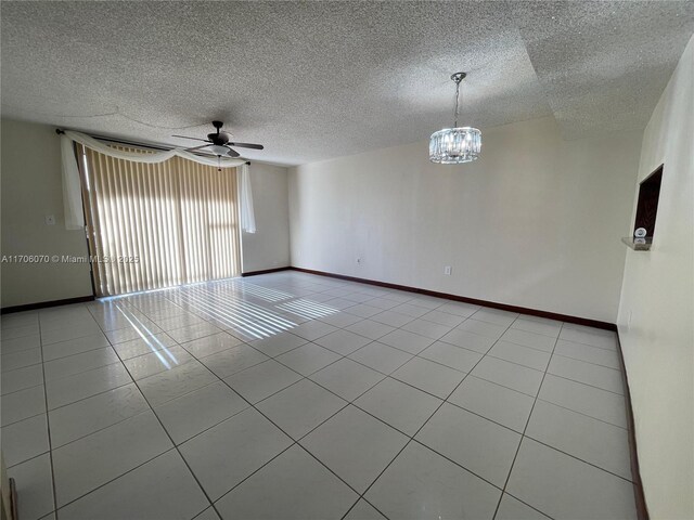 unfurnished room with ceiling fan with notable chandelier, light tile patterned floors, and a textured ceiling