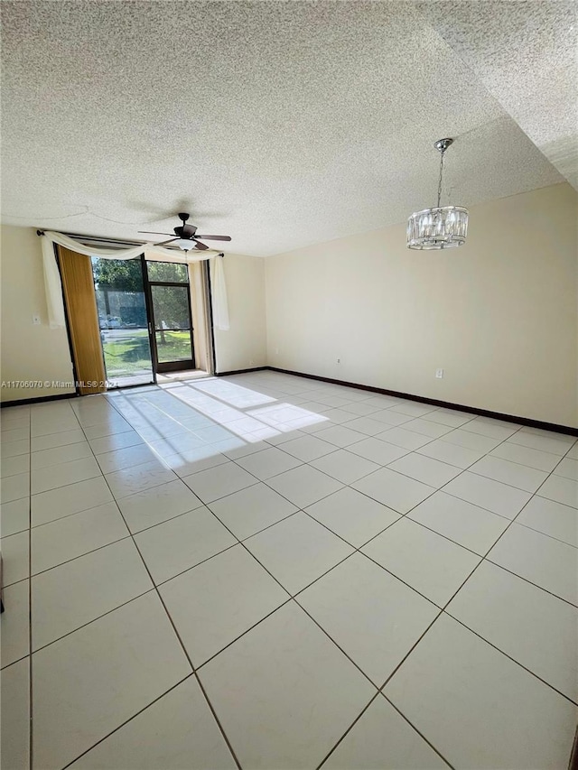 empty room featuring light tile patterned floors, ceiling fan with notable chandelier, and a textured ceiling