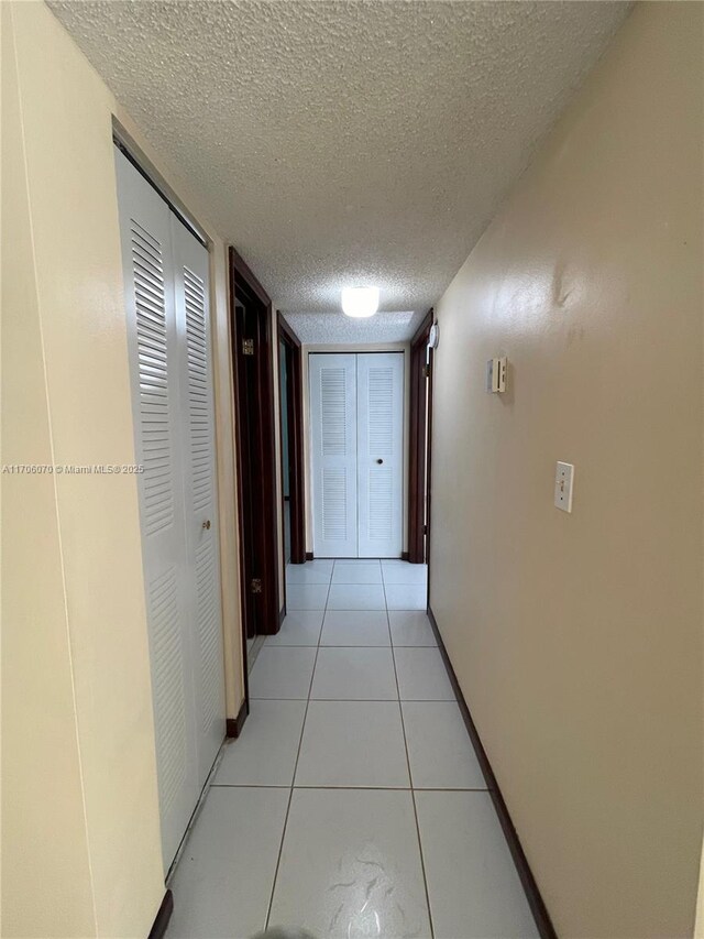 hallway featuring light tile patterned floors and a textured ceiling