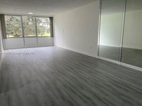 unfurnished bedroom with a textured ceiling, dark hardwood / wood-style floors, and a closet