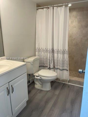 bathroom featuring hardwood / wood-style floors, vanity, toilet, and a shower with curtain