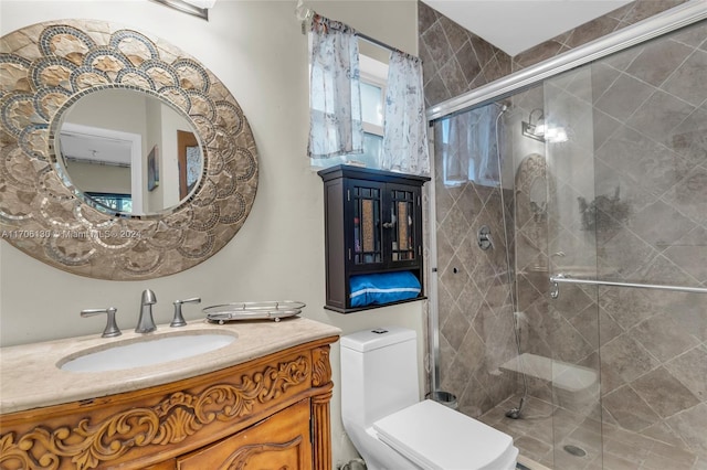 bathroom with vanity, toilet, and a shower with door