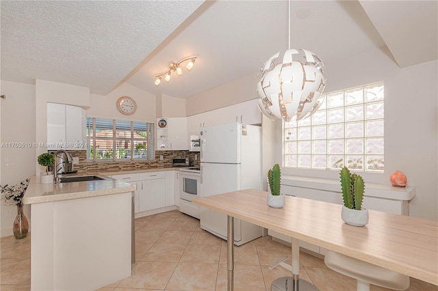 kitchen featuring lofted ceiling, white appliances, sink, tasteful backsplash, and white cabinetry