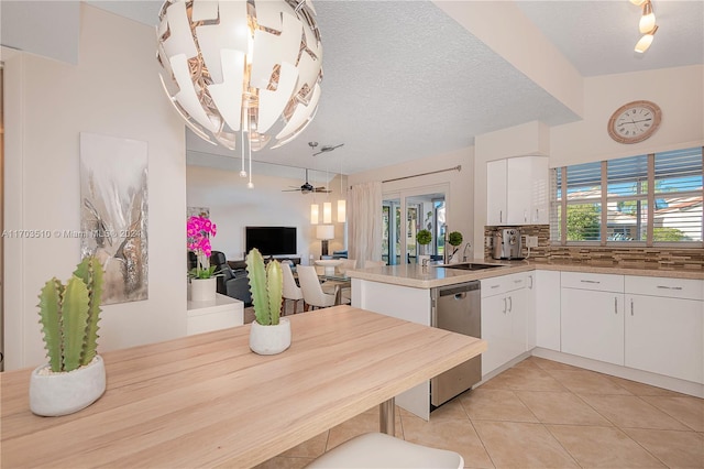 kitchen featuring kitchen peninsula, white cabinetry, ceiling fan, and stainless steel dishwasher