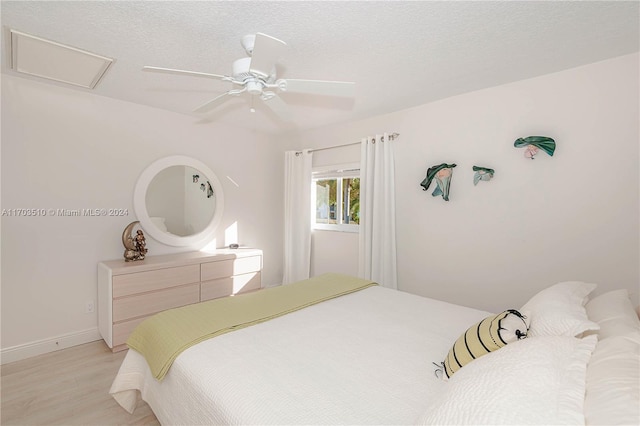 bedroom featuring ceiling fan, a textured ceiling, and light wood-type flooring