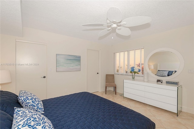 bedroom featuring ceiling fan, light tile patterned floors, and a textured ceiling