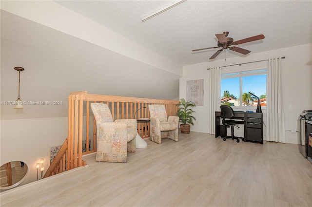 interior space featuring ceiling fan, light hardwood / wood-style floors, and a textured ceiling