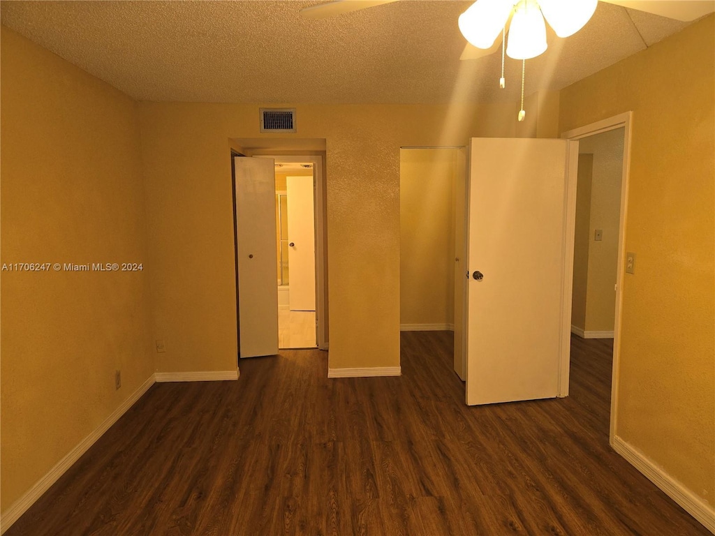 unfurnished bedroom with a textured ceiling, ceiling fan, and dark wood-type flooring