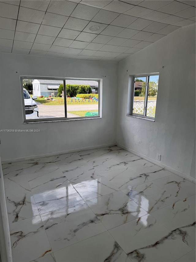 empty room featuring a paneled ceiling and a wealth of natural light