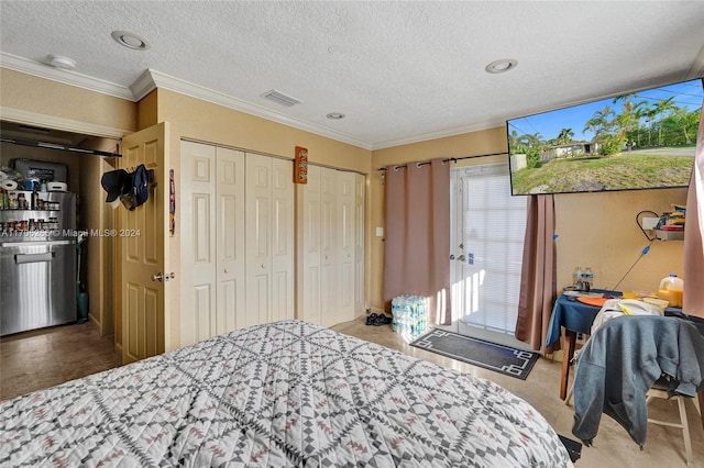 bedroom featuring a textured ceiling, crown molding, and multiple closets