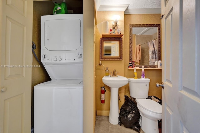 bathroom featuring tile patterned floors, a textured ceiling, crown molding, toilet, and stacked washer / drying machine