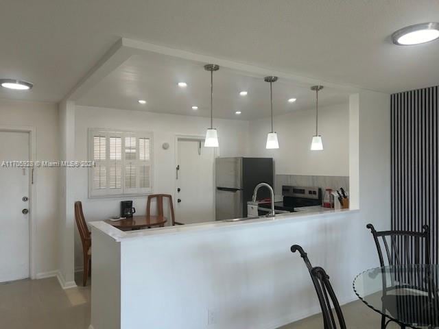 kitchen featuring kitchen peninsula, pendant lighting, decorative backsplash, and appliances with stainless steel finishes