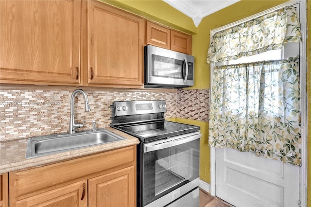 kitchen featuring tasteful backsplash, ornamental molding, stainless steel appliances, sink, and wood-type flooring
