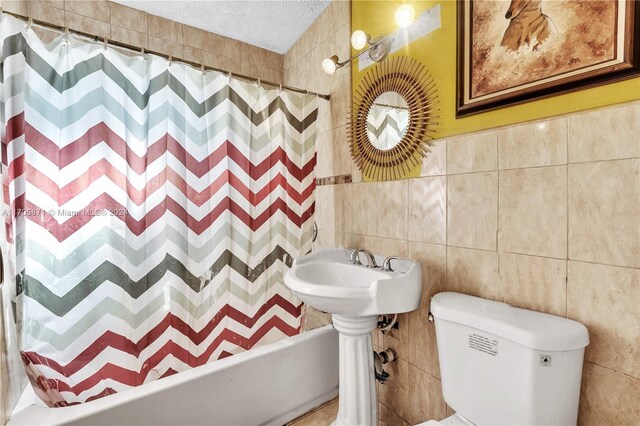 bathroom featuring a textured ceiling, toilet, and tile walls