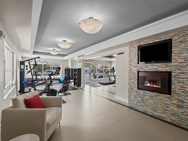 gym featuring a raised ceiling and light tile patterned flooring