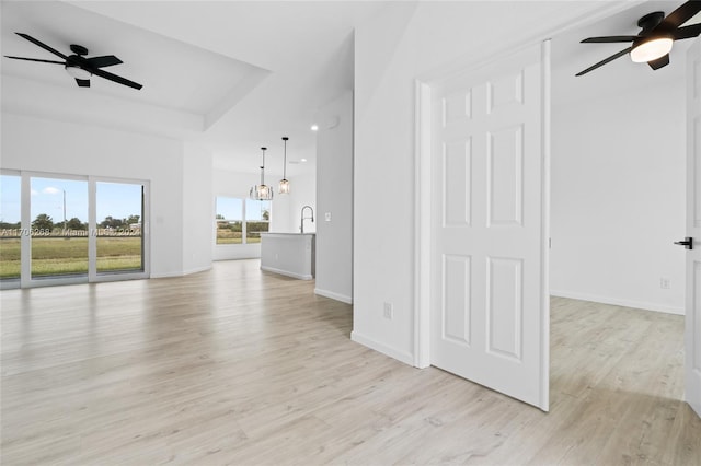 unfurnished living room featuring ceiling fan with notable chandelier, light hardwood / wood-style flooring, and sink