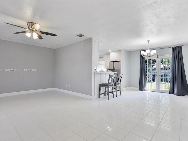 spare room featuring french doors, ceiling fan with notable chandelier, a textured ceiling, and light tile patterned floors