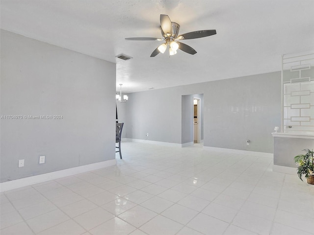 unfurnished room featuring a textured ceiling, light tile patterned flooring, and ceiling fan with notable chandelier