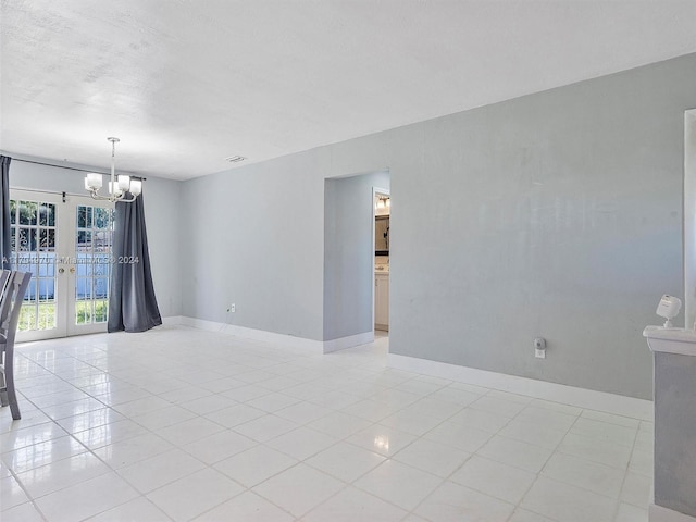 tiled empty room with an inviting chandelier and french doors