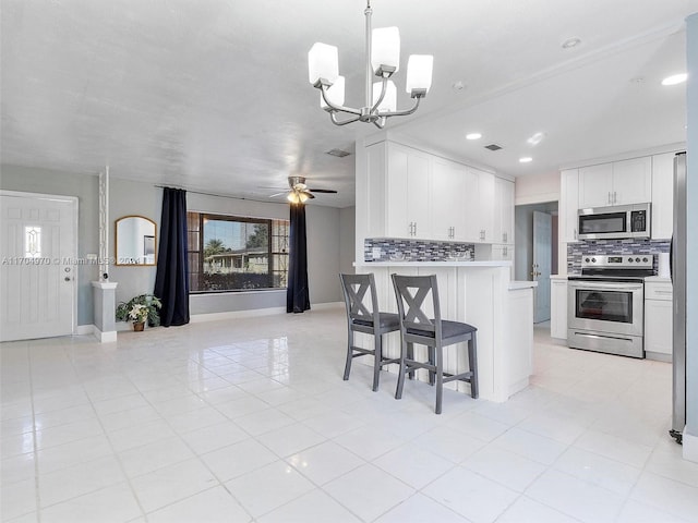 kitchen featuring backsplash, white cabinets, ceiling fan with notable chandelier, hanging light fixtures, and stainless steel appliances