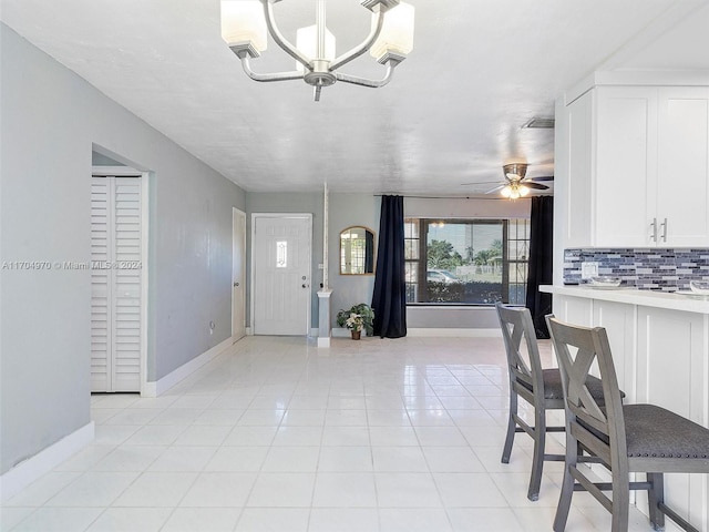 dining space with light tile patterned floors and ceiling fan with notable chandelier