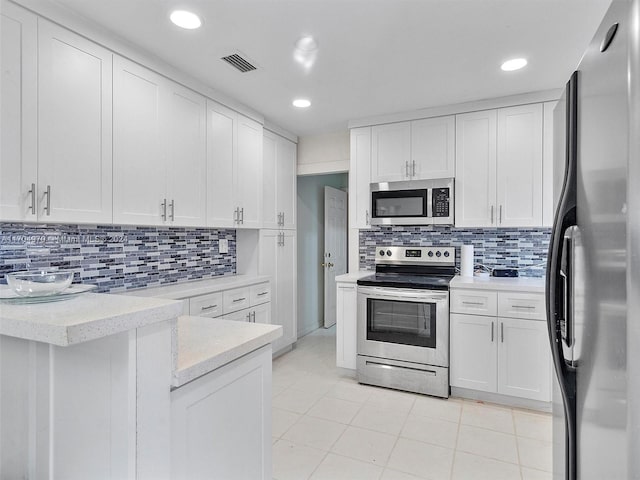 kitchen featuring tasteful backsplash, white cabinetry, light tile patterned flooring, and appliances with stainless steel finishes