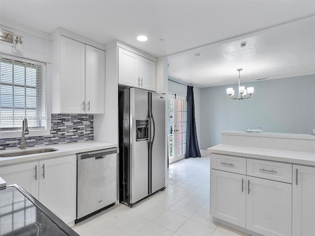 kitchen with appliances with stainless steel finishes, tasteful backsplash, sink, pendant lighting, and white cabinets