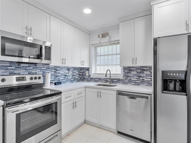 kitchen with sink, stainless steel appliances, light tile patterned floors, decorative backsplash, and white cabinets