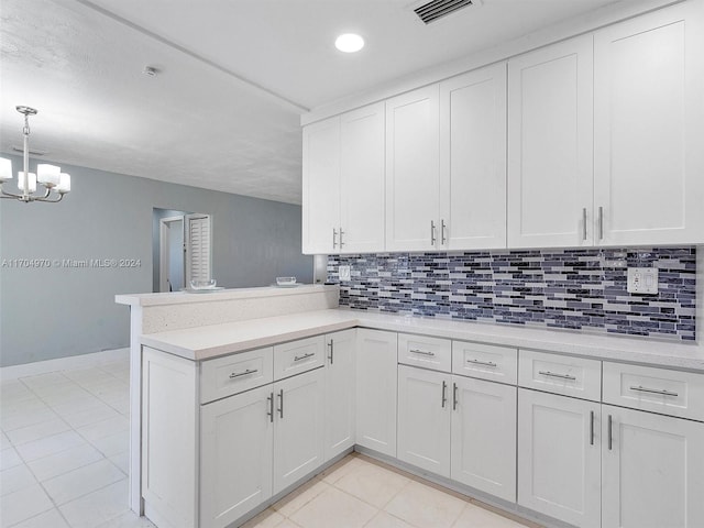 kitchen featuring kitchen peninsula, backsplash, white cabinets, and hanging light fixtures