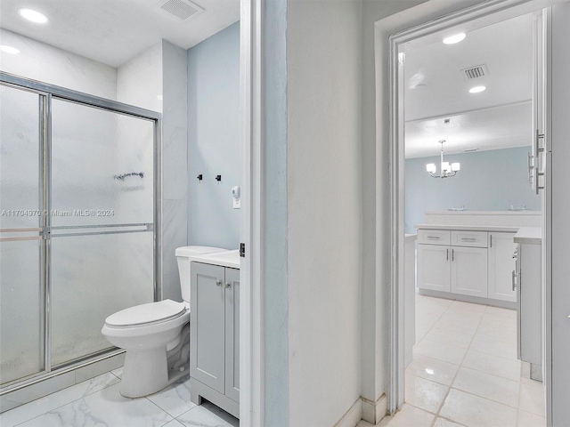 bathroom with a chandelier, vanity, toilet, and a shower with door