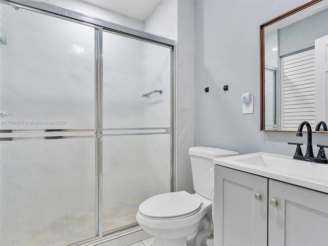 bathroom featuring tile patterned flooring, vanity, toilet, and walk in shower