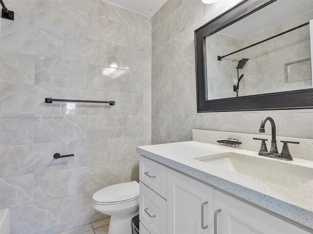 bathroom with tile patterned floors, vanity, toilet, and tile walls