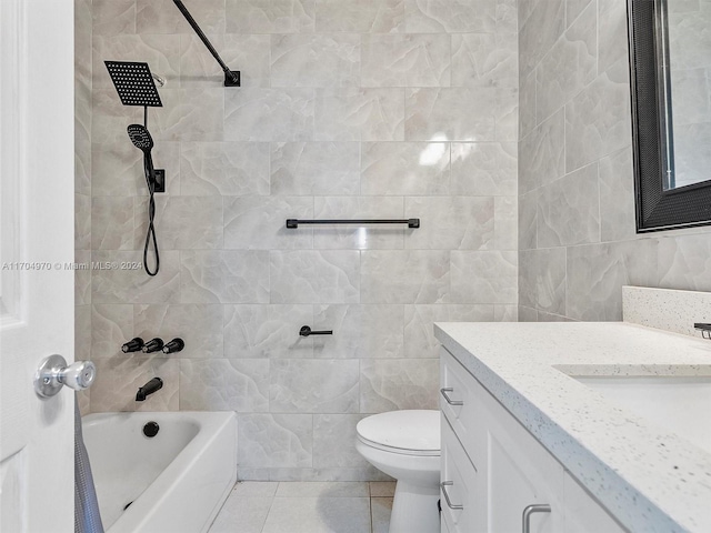 full bathroom with tile patterned floors, toilet, vanity, tile walls, and tiled shower / bath