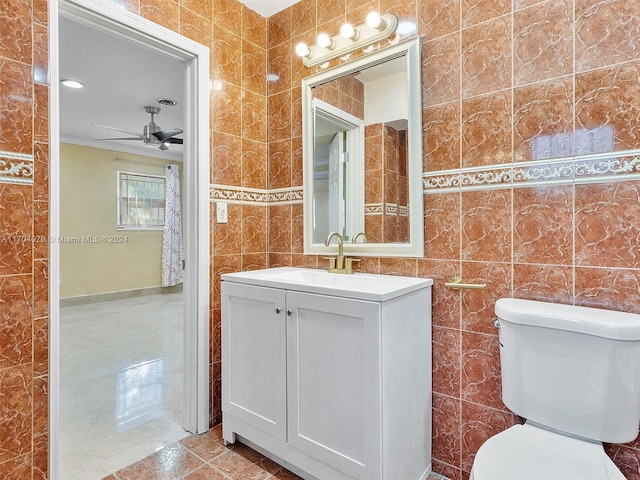 bathroom with ceiling fan, vanity, tile walls, and toilet